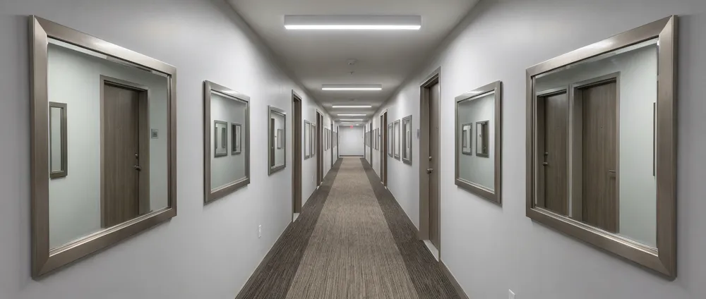 Multi-unit residential building hallway with standardized mirror installations
