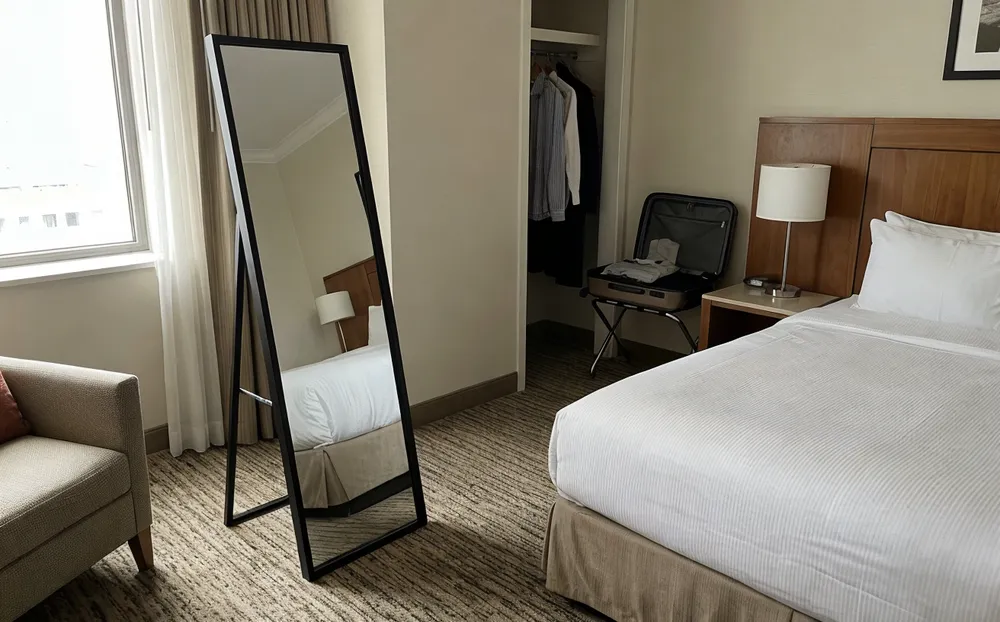Easel-back floor mirror in hotel room interior with consistent finish across property
