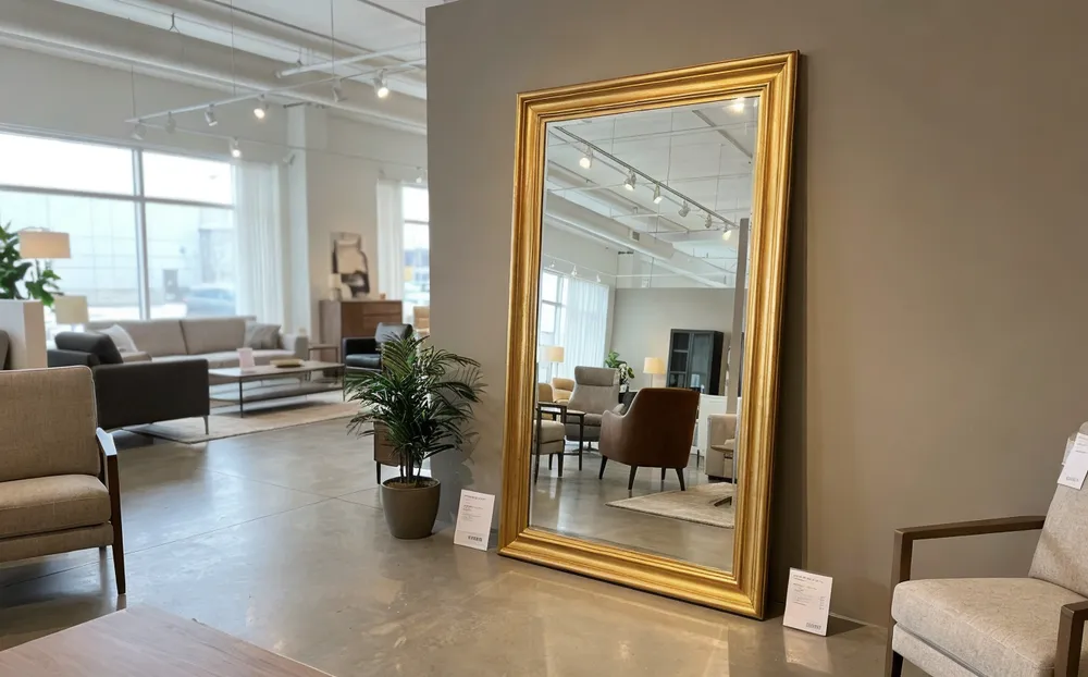 Large floor-leaning mirror with premium frame in furniture retail showroom