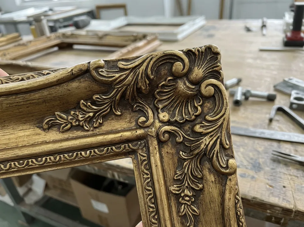 Close-up of deep-relief resin frame showing scrollwork detail and antiqued gold finish